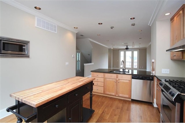 kitchen with a peninsula, a sink, visible vents, appliances with stainless steel finishes, and crown molding