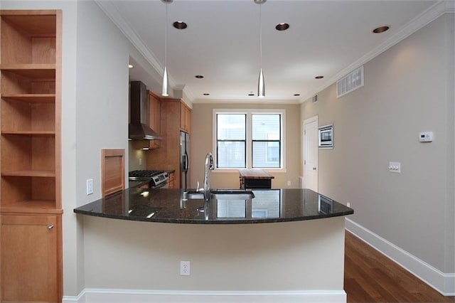 kitchen with wall chimney exhaust hood, brown cabinets, stainless steel appliances, crown molding, and a sink