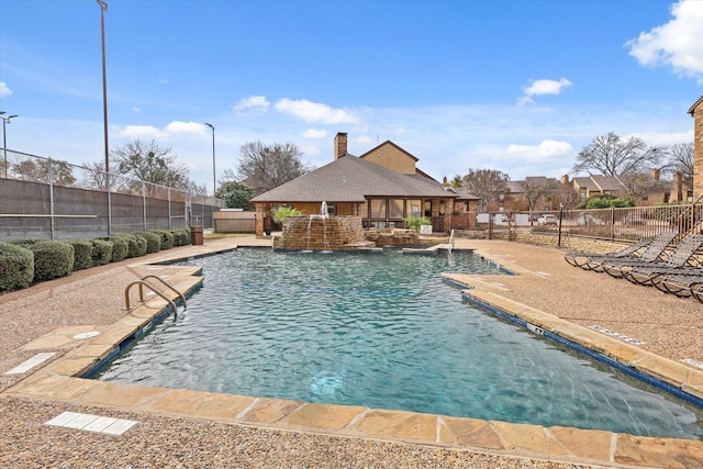 pool featuring fence private yard, a patio, an outdoor structure, and a storage structure