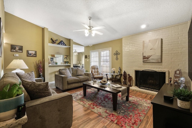 living area with ceiling fan, vaulted ceiling, a fireplace, and wood finished floors