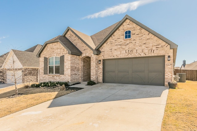 french country style house featuring concrete driveway, brick siding, an attached garage, and roof with shingles