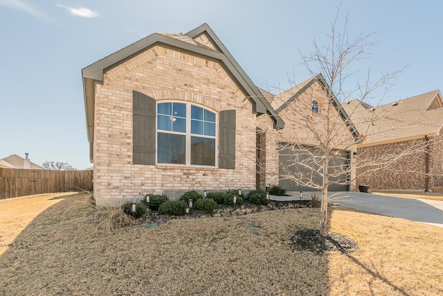 view of front of property featuring concrete driveway, brick siding, fence, and an attached garage