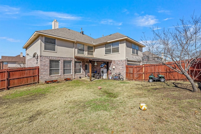 rear view of house with brick siding, a yard, a chimney, and a fenced backyard