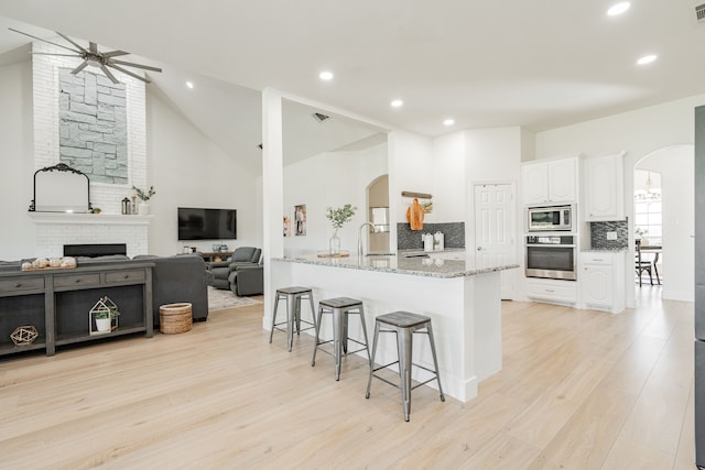 kitchen featuring stainless steel appliances, arched walkways, white cabinets, and a breakfast bar area