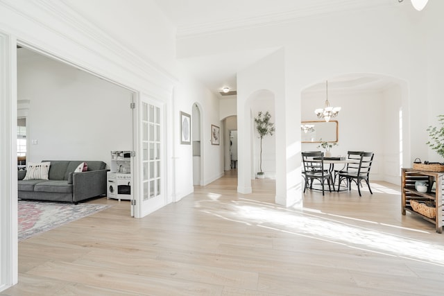 interior space with arched walkways, ornamental molding, wood finished floors, and a notable chandelier