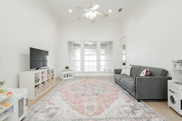 living area featuring recessed lighting, visible vents, ornamental molding, light wood-style floors, and a ceiling fan