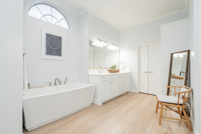 full bath with crown molding, vanity, a freestanding bath, and wood finished floors