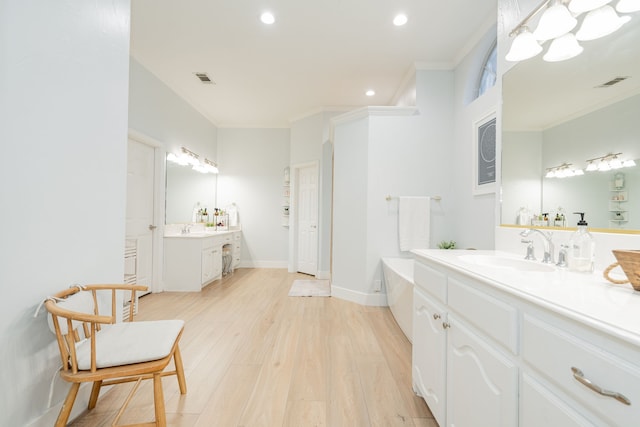 full bathroom featuring visible vents, wood finished floors, a sink, and ornamental molding