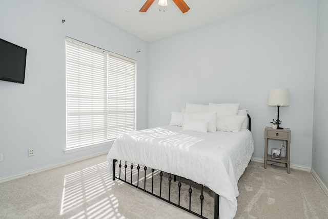 carpeted bedroom featuring a ceiling fan, multiple windows, and baseboards