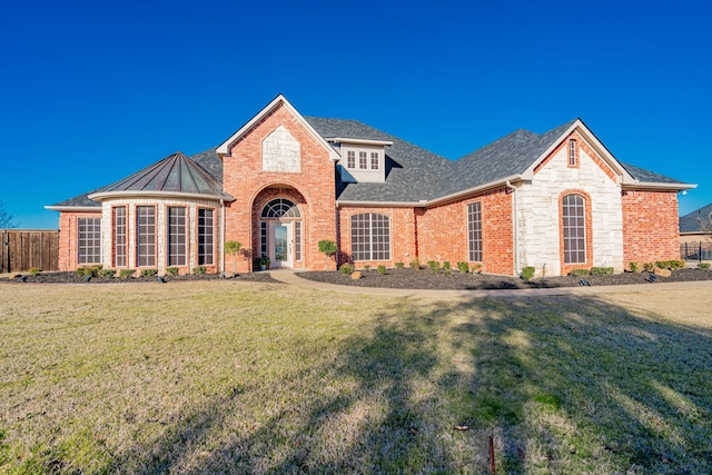 view of front of house featuring stone siding, brick siding, fence, and a front lawn