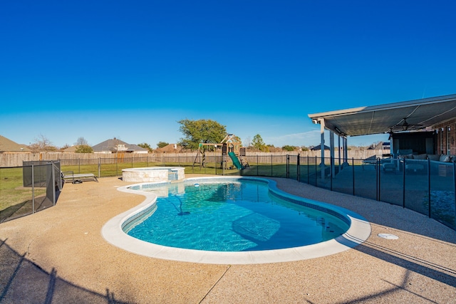 view of swimming pool featuring a fenced backyard, a pool with connected hot tub, a playground, and a patio