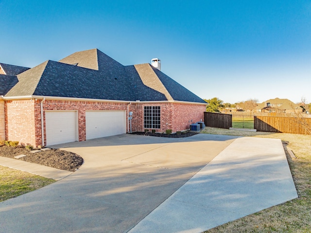 view of front facade featuring brick siding, roof with shingles, a chimney, an attached garage, and fence