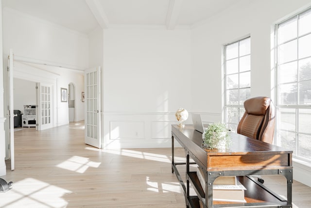 home office with a wealth of natural light, light wood-style flooring, beamed ceiling, and french doors