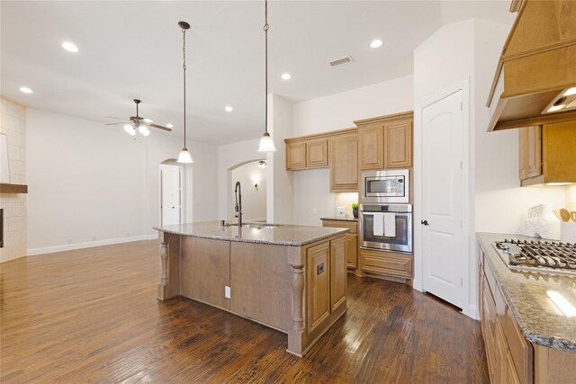 kitchen featuring custom exhaust hood, arched walkways, a sink, ceiling fan, and stainless steel appliances