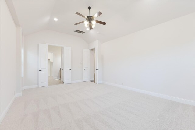 unfurnished bedroom with visible vents, light carpet, baseboards, and vaulted ceiling