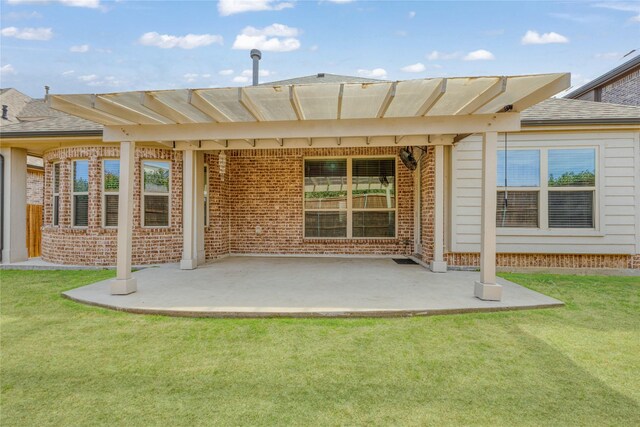 rear view of house featuring a patio, a yard, and brick siding