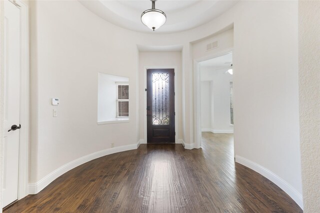 foyer entrance with dark wood finished floors, baseboards, and visible vents