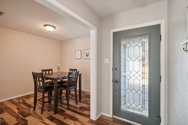 foyer featuring a textured ceiling, wood finished floors, visible vents, and baseboards