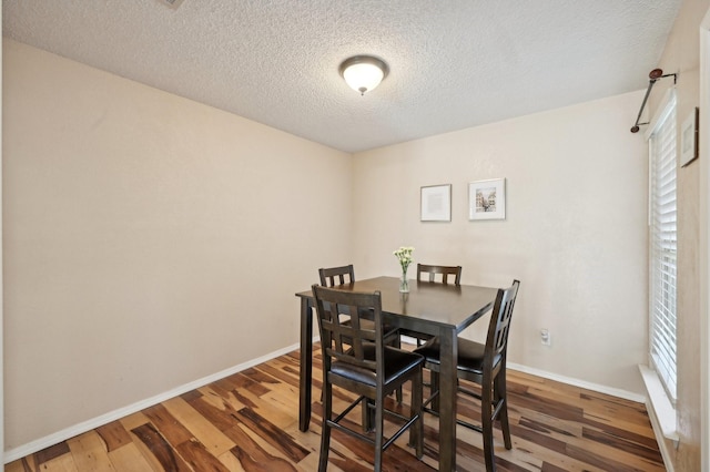 dining area with a wealth of natural light, baseboards, and wood finished floors