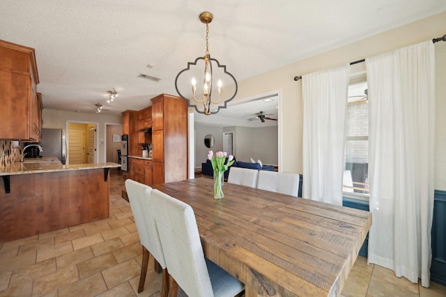 dining area with visible vents, a textured ceiling, and ceiling fan with notable chandelier