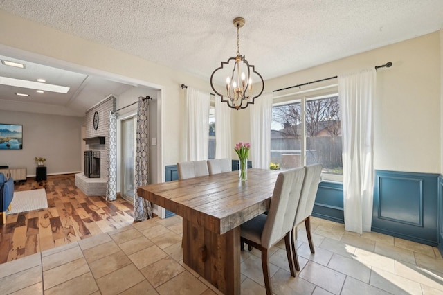 dining space featuring an inviting chandelier, a fireplace, a textured ceiling, and light tile patterned flooring