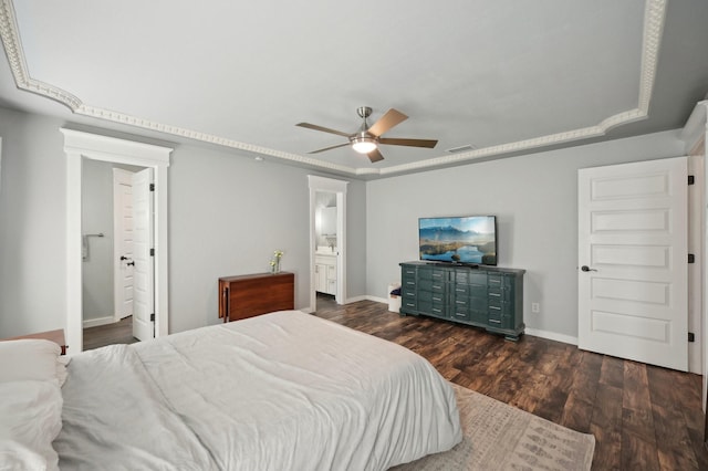 bedroom with connected bathroom, baseboards, a raised ceiling, and wood finished floors