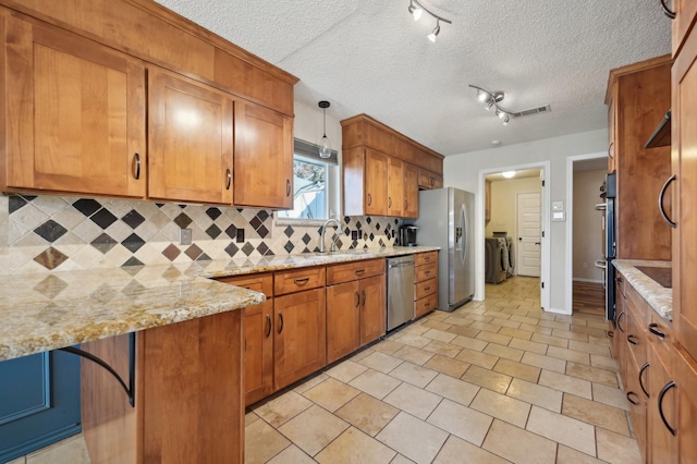 kitchen with stainless steel appliances, separate washer and dryer, a sink, and brown cabinets