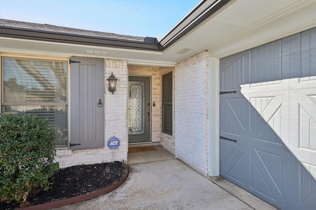 view of exterior entry featuring brick siding and an attached garage