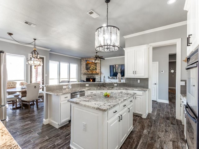 kitchen featuring a peninsula, a sink, visible vents, backsplash, and dark wood-style floors