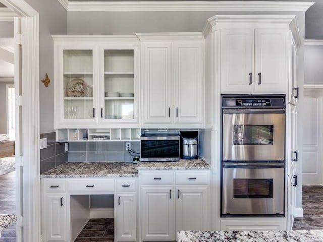 kitchen featuring white cabinetry, stainless steel double oven, and wood finished floors