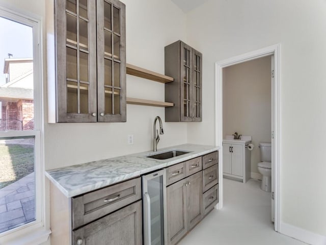 kitchen featuring wine cooler, glass insert cabinets, gray cabinetry, open shelves, and a sink