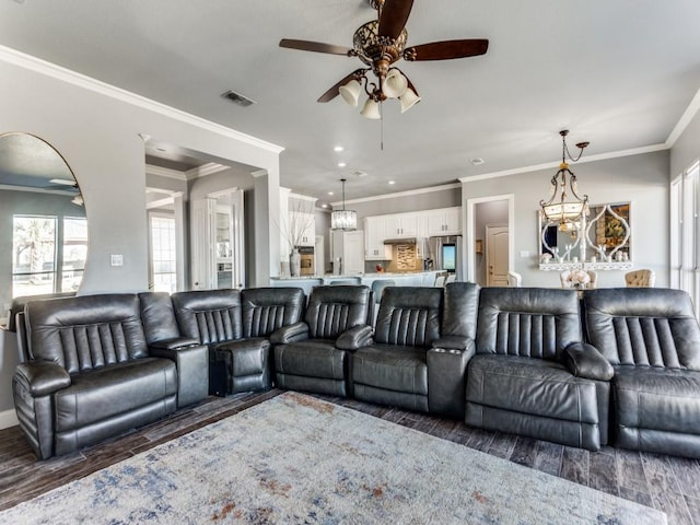 living area featuring ornamental molding, ceiling fan with notable chandelier, visible vents, and wood finished floors