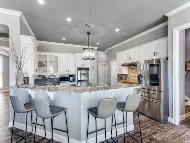 kitchen featuring stainless steel appliances, dark wood finished floors, visible vents, and a sink