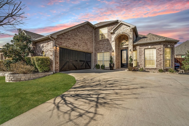 view of front facade with a garage, a front yard, brick siding, and driveway