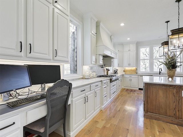 interior space with white cabinetry, premium range hood, stainless steel gas cooktop, and light countertops