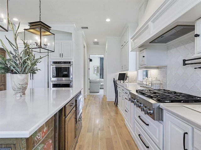 kitchen with light wood finished floors, tasteful backsplash, white cabinets, stainless steel appliances, and light countertops