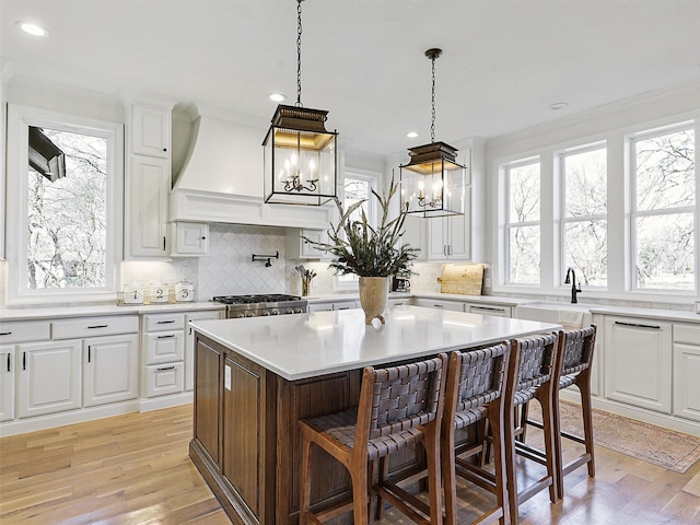 kitchen featuring light wood-style flooring, a breakfast bar area, white cabinetry, and tasteful backsplash