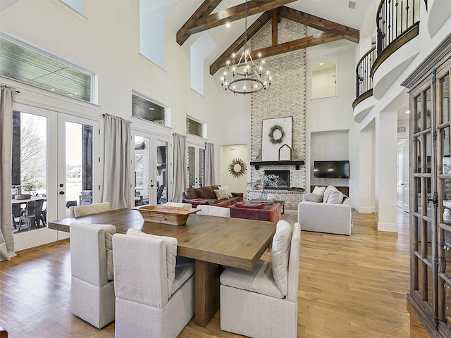 dining room with light wood finished floors, a fireplace, a notable chandelier, and french doors