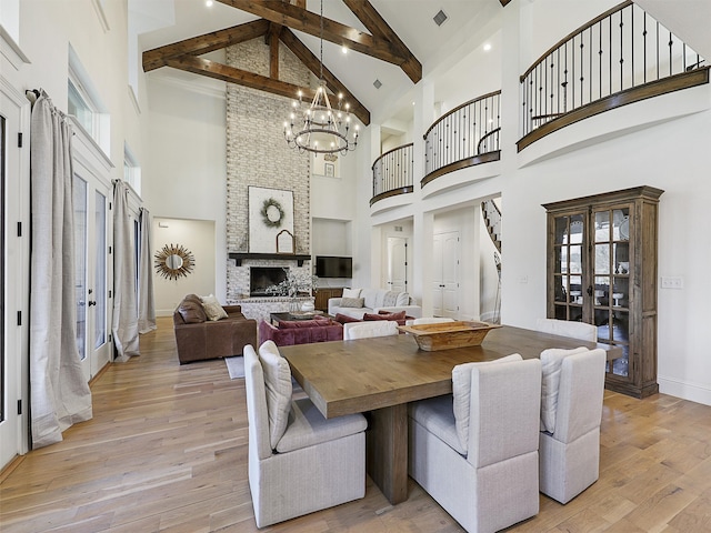 dining area with french doors, a high ceiling, a large fireplace, and light wood finished floors