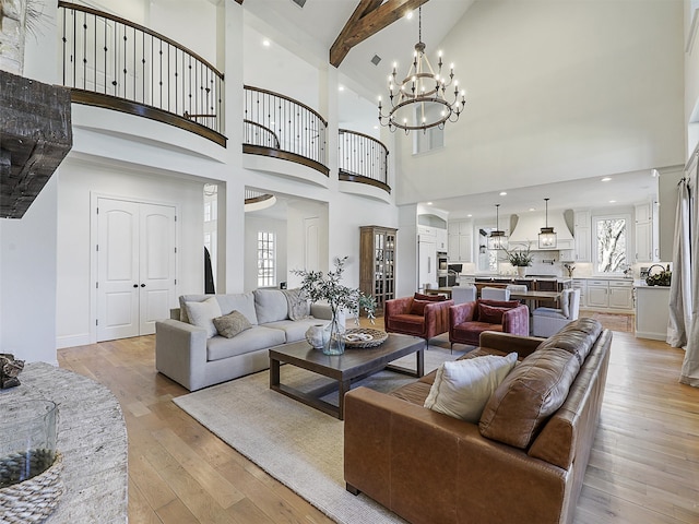 living room with a towering ceiling, plenty of natural light, beamed ceiling, and light wood finished floors