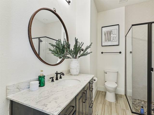 bathroom with toilet, a shower stall, baseboards, and vanity