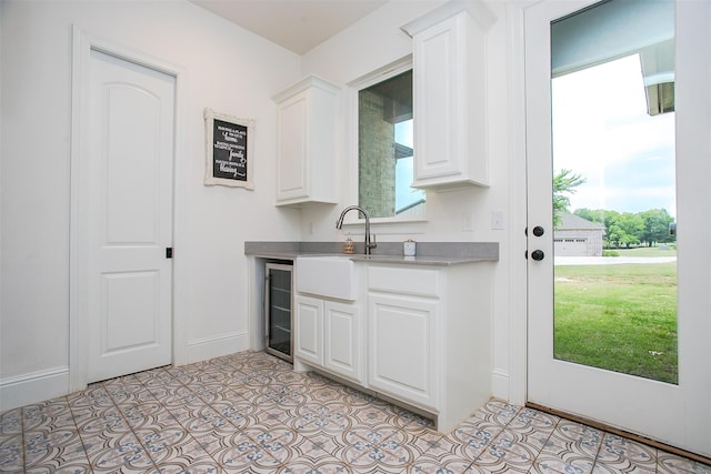 bar featuring light tile patterned floors, wine cooler, baseboards, and a sink