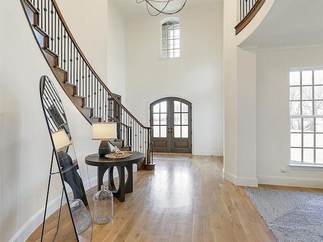 foyer with ornamental molding, arched walkways, french doors, and wood finished floors