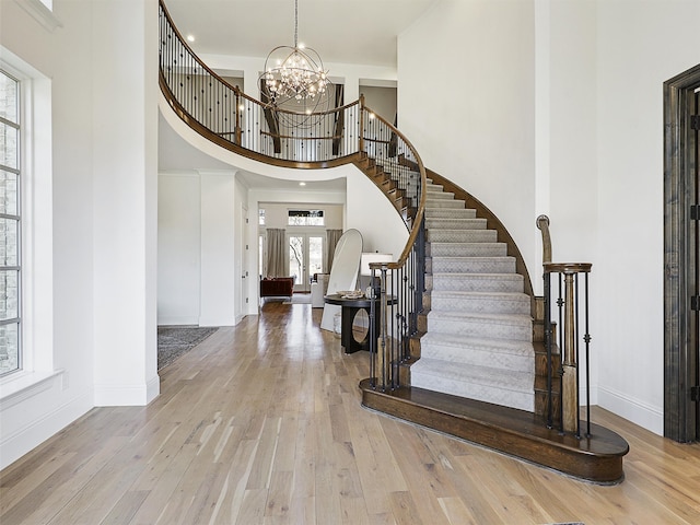 entrance foyer with stairway, a high ceiling, a chandelier, baseboards, and hardwood / wood-style flooring