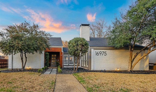 view of front of home with a chimney and a lawn