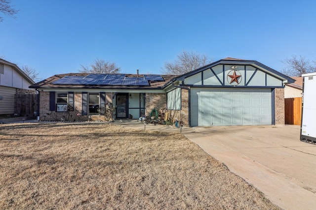 ranch-style house with driveway, fence, solar panels, and brick siding