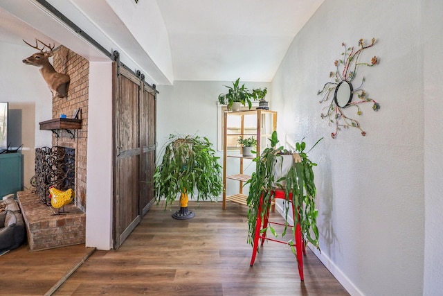 hall featuring a barn door, baseboards, vaulted ceiling, and wood finished floors