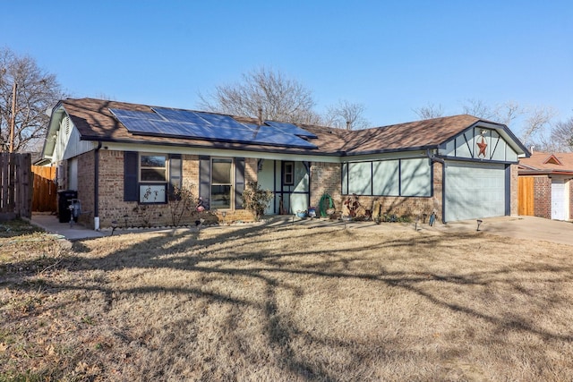 view of front of house featuring solar panels, an attached garage, fence, a front lawn, and brick siding