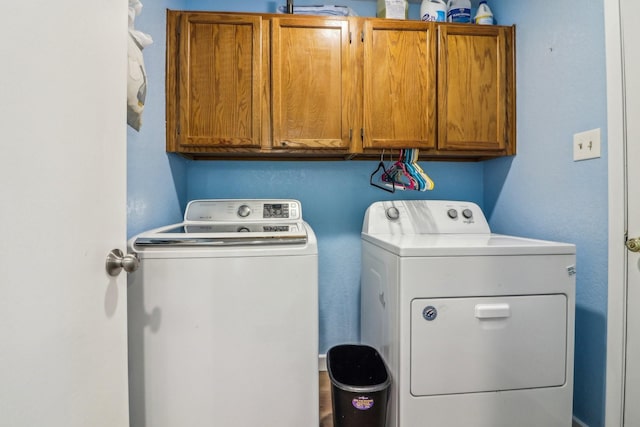 clothes washing area featuring cabinet space and separate washer and dryer