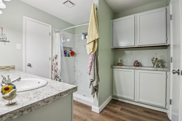 bathroom with a stall shower, visible vents, wood finished floors, and vanity